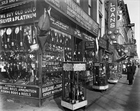 Stuyvesant Curiosity shop, with guns, binoculars, in cases in front; instruments, knives, other goods in window; loan and 'fat men's' shop. Pawn Shop, 48 Third Avenue, Manhattan. ca. 1937