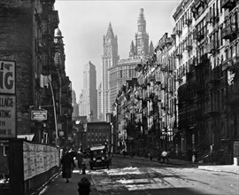 1930s New York City - Snow remains in the shady parts of Henry Street which is lined with 6-7-story buildings, the Municipal and other buildings rise above end of st.