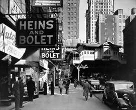 Radio Row, Cortlandt Street, Manhattan New York City - Men window shop in store selling radios, elevated railroad station, Ninth Avenue line, right center, subway entrance visible. ca. 1936