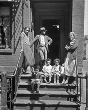 Three generations of African Americans on stoop of brick home with iron rails on steps. Jay Street, No. 115, Brooklyn ca. 1936