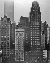 View from across the Bryant Park, incl. Scientific American, American Radiator Bldgs., corner of the library; Empire State Building beyond. 40th Street between Fifth and Sixth Avenues, Manhattan ca. 1...