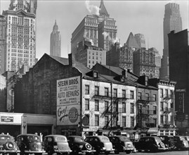 1930s New York City - In Manhattan 1930s, Cars parked along street in front of Stern Bros. Auto Repairs, at left and 4-story Cortland Hotel, right, tall buildings beyond