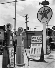 Texaco Gasoline station, Tremont Avenue and Dock Street, Bronx. Four gas pumps and tall Texaco sign at Abe's Plaza Gas station, with price for gas listed at 11 2/10 cents, cars washed for 95 cents.ca....