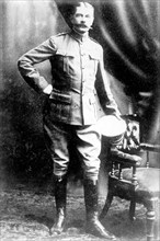 Lord Kitchener, standing by chair, in uniform