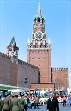 Pedestrians and soldiers walk outside Kremlin walls and Kremlin Clock tower high above them in Moscow Soviet Union in late 1970s (1978)