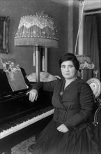 Amy Castles, three-quarters length portrait, seated at piano, facing slightly left. Australian singer
