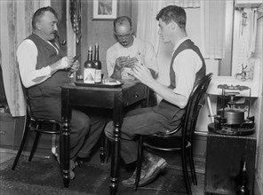 Men playing cards next to a primus stove in a home in Broad Channel, Queens ca. 1910-1915