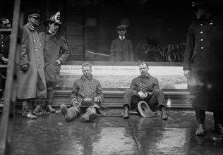 Firemen seated on the sidewalk after fighting a fire in a New York City subway tunnel which took place near West 55th Street and Broadway, January 6, 1915