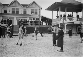 People on the beach at Coney Island throwing balls (possibly medicine balls) ca. January 1915