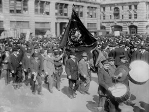 Men with a banner for the Brotherhood of Carpenters and Joiners of America, marching in a procession on May Day, 1914