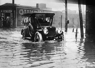 Man driving car through flooded street in Cleveland Ohio ca. 1910-1915