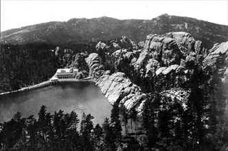 This historical photo of Sylvan Lake in Custer County, South Dakota shows characteristic erosion forms in the massive granite structures next to Sylvan Lake Lodge. In the distance is Harney Peak.