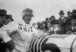 Racecar driver Gil Andersen standing next to his Stutz White Squadron racer ca. 1915