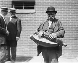 A street musician playing a hurdy-gurdy ca. 1910-1915