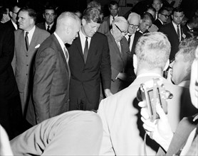 (1962) Astronaut John H. Glenn Jr., gives United States President John F. Kennedy a quick run-down on the display of survival gear.