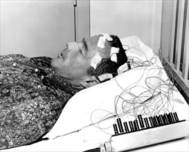 (1962) Mercury astronaut M. Scott Carpenter lies on a bed with biosensors attached to his head during astronaut training activities at Cape Canaveral