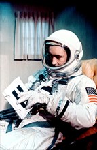 (3 June 1965) Astronaut James A. McDivitt, Gemini-4 command pilot, is shown in full spacesuit in the suit trailer prior to launch. He is reviewing a crew procedures flip book.