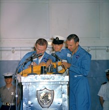 (18 Dec. 1965) Astronauts Frank Borman (left), Gemini-7 command pilot, and James A. Lovell Jr., pilot, take time out during their welcoming ceremonies aboard the aircraft carrier USS Wasp to autograph...