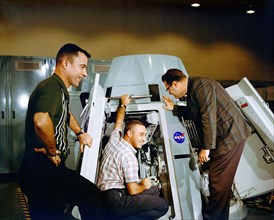 (19 Nov. 1964) Astronauts Virgil I. Grissom (center) and John W. Young (left), prime crew for the Gemini-Titan 3 mission, are shown inspecting the inside of Gemini spacecraft at the Mission Control Ce...