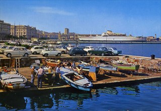 Old postcard of the squero of the Grand Canal of Trieste, people putting boats in water  ca. 1960