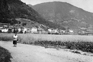 Woman walking down a road outside Cembra (Cembra Lisignago, Trentino, Italy) ca. 1960s or earlier
