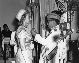 His Highness the Sultan pinning the Sultan Omar Ali Saifuddin medal on Mrs. M. E. Lloyd-Dolbey ca. 1960