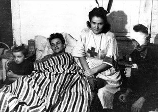Warsaw Uprising: Nurse Janina Steczniewska "Inka" with daughter Hania and wounded insurgent Edmund Michniewski "Mis" in the hospital of "Koszta" Company ca. August 1944