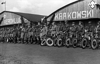Cyclists with decorated bikes in front of the hangar of the Krakow Aeroclub at the Rakowicki airport ca. May 1, 1937