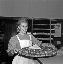 A woman carrying a platter of paczki (filled doughnuts) at Blikle pastry shop in Warsaw ca. 1969-1978