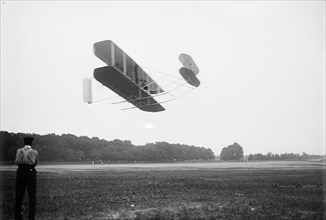 Orville Wright and airplane (aeroplane), in flight over field 7 1 1909