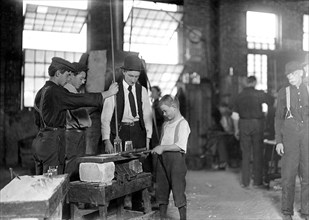 Teaching the young idea. The boss (who began at 10 years of age, and has been at it for 30 years) showing a beginner (who is apparently 9 or 10), October 1908