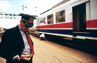 Conductor checks his watch, Bloomington, Illinois, stop on the turboliner run between St. Louis,