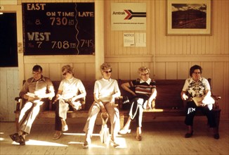 Passengers waiting in the station at East Glacier Park Montana, for the train which will take them to Seattle, Washington, June 1974