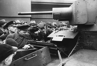 A group of Germans is watching a captured Polish 7TP tank exhibited at the Leipzig Fair. The hole described in chalk after being hit by a 20 mm bullet is visible ca. 1939