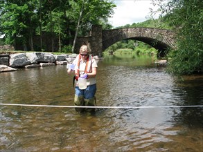 USGS hydrologist collecting a water quality sample from a NY stream ca. June 2010