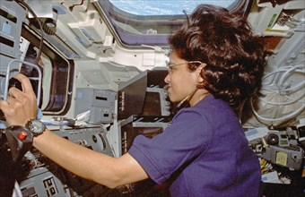 Chawla is photographed at the aft flight deck station controlling the RMS