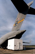 Workers offload the shipping container with the Cassini orbiter from what looks like a giant shark mouth, but is really an Air Force C-17 air cargo plane ca. 1997