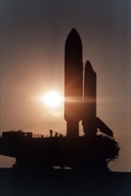 Cast in silhouette by the rising sun, the Space Shuttle Atlantis slowly and carefully makes the journey along the Crawlerway between the Vehicle Assembly Building and Launch Pad 39A ca. 1997