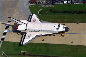 Carried atop an orbiter transporter, the Space Shuttle orbiter Atlantis makes the short journey from Orbiter Processing Facility Bay 3 to the Vehicle Assembly Building (VAB) ca. 1997