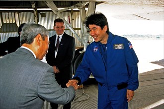 STS-87 Mission Specialist Takao Doi, Ph.D., of the National Space Development Agency (NASDA) of Japan greets a NASDA official shortly after the orbiter Columbia returned to KSC ca. 1997