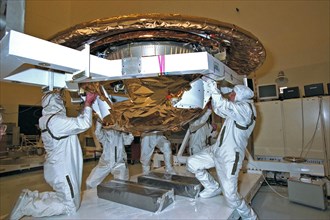 Dornier Satelliten Systeme (DSS) workers place the back cover of the Huygens probe under its front heat shield in the Payload Hazardous Servicing Facility (PHSF) at KSC ca. 1997
