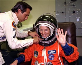 With the assistance of a suit technician, STS-84 Pilot Eileen Marie Collins finishes donning her launch and entry suit in the Operations and Checkout Building ca. 1997