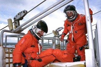 STS-85 Pilot Kent V. Rominger (left) and  Commander Curtis L. Brown, Jr. exit an emergency egress slidewire basket at the 195-foot level of Launch Pad 39A during Terminal Countdown Demonstration Test ...
