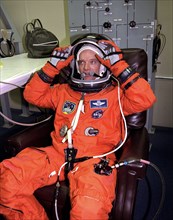 STS-84 Commander Charles Precourt adjusts the helmet of his launch and entry suit during final prelaunch preparations in the Operations and Checkout Building ca. 1997