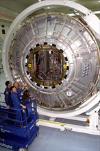 Members of the STS-88 crew examine the Node 1 of the International Space Station in the high bay of the Space Station Processing Facility ca. 1997