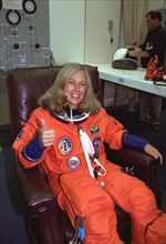 STS-85 Payload Commander N. Jan Davis gives a thumbs up as she is assisted with her ascent/reentry flight suit in the Operations and Checkout (O&C) Building ca. 1997