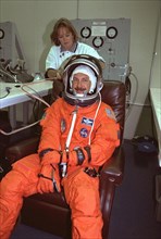 STS-85 Commander Curtis L. Brown, Jr. smiles as he is assisted with his ascent/reentry flight suit by a suit technician in the Operations and Checkout (O&C) Building ca. 1997