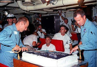(29 Aug. 1965) --- Astronauts Charles Conrad Jr. (left) and L. Gordon Cooper Jr. prepare to slice into the huge cake prepared for them by the cooks onboard the aircraft carrier USS Lake Champlain.