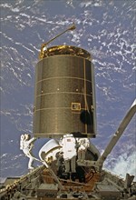 In this onboard photo, astronauts Hieb, Akers, and Thuot have handholds on the INTELSAT VI satellite, a communications satellite for the International Telecommunication Satellite organization.