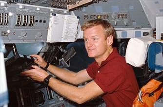 1990 STS-36 Pilot Casper reaches for laptop computer on OV-104's flight deck